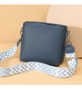 Close-up of pebble grain leather crossbody bag with geometric pattern wide strap