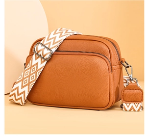 Détail d'un sac à bandoulière marron texturé avec une large sangle géométrique