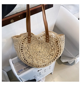 Detail of hand-woven beige straw tote with premium brown leather handles and stitching
