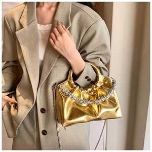 Detail of metallic gold pleated PU bag with silver chain worn with a blazer