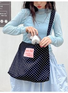 Detailed macro of the black canvas bag with white polka dots and pink logo patch