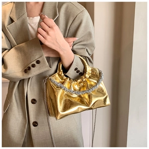 Detail of trendy gold PU shoulder bag with pleated texture and silver chunky chain strap