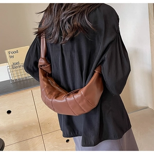 Detail showing the brown PU leather crescent bag with pleated stitching and a knotted strap