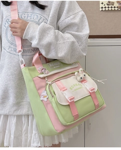 Side view of a mint green and pink nylon crossbody bag with cute bunny charms for women