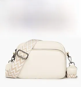 Gros plan d'un sac bandoulière blanc à motif litchi avec bandoulière tissée géométrique