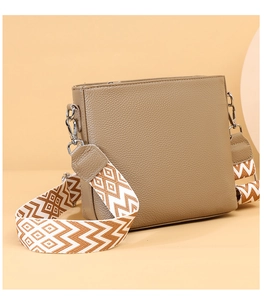 Detailed macro of pebble leather crossbody bag with geometric pattern wide strap
