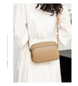 Detail of khaki pebbled leather crossbody bag with double zipper and stylish woven strap