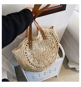 Detailed close-up of natural straw weave texture and brown leather strap on a tote bag