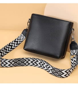 Close-up of black lychee texture leather bag with a stylish geometric woven shoulder strap