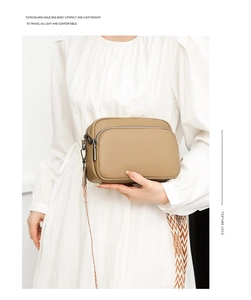 Detail of khaki pebbled leather crossbody bag with wide geometric woven strap