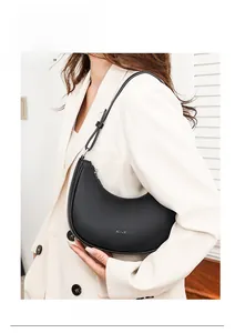Close-up of a minimalist black crescent shoulder bag in premium pebble leather on a model
