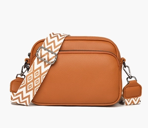 Détail du sac photo marron avec bandoulière large à motifs géométriques et boucles argentées