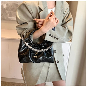 Detail of black faux leather cloud bag with silver thick chain and thin metal strap