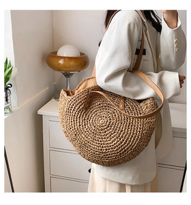 Detail of hand-woven straw texture and brown PU leather strap on a semi-round summer bag