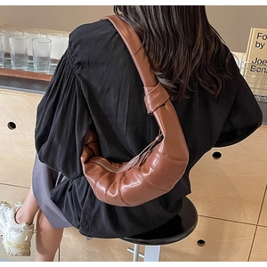 Detail of a brown PU leather croissant bag with quilted pleats and knotted strap detail