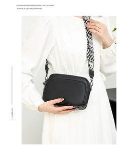 Detail of black lychee grain leather crossbody bag with a geometric pattern strap