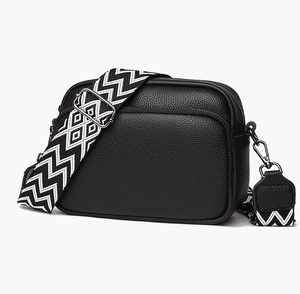 Détail du sac à bandoulière en cuir noir avec double fermeture éclair et sangle tissée