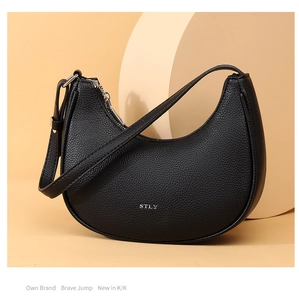 Detail shot of the textured black leather finish and silver STLY logo on the hobo bag