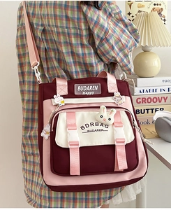 Close-up detail of color-block nylon crossbody bag with buckle pockets and rabbit charm