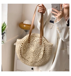 Detail of circular woven straw tote bag featuring brown leather handles and textures