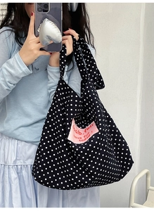 Close-up of black polka dot canvas tote bag featuring pink Gab.feli logo patch