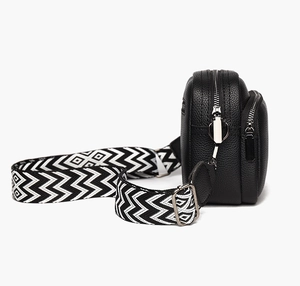 Détail du sac bandoulière noir en cuir grainé avec double zip et sangle géométrique