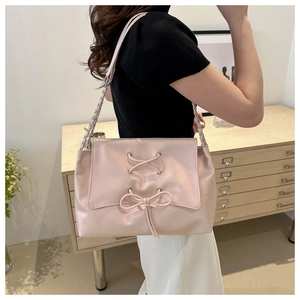 Detail of light pink tote bag with bow tie design and silver chain strap on shoulder