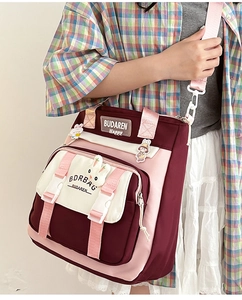 Detailed shot of a red and pink nylon crossbody bag with cute rabbit pendant and wide strap