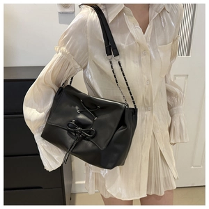 Detail of black PU leather tote with cross-tie bow and mixed chain shoulder strap