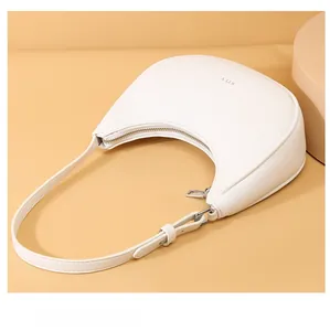 Detail of white lychee leather texture on a minimalist crescent underarm bag with silver zipper