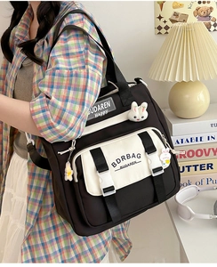 Detail shot of canvas crossbody bag featuring plush bunny charms and brand logo print