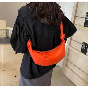 Chic orange PU leather crescent bag with quilted stitching on a female model