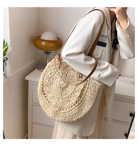 Detail of a large woven straw shoulder bag with elegant brown leather straps and texture