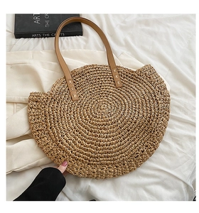 Detail of hand-woven round straw tote bag with scalloped edges and leather handles