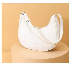 Detail of white lychee leather texture on crescent bag with embossed STLY logo and silver buckle