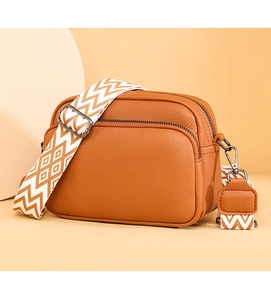Vue détaillée du sac bandoulière en cuir grainé marron avec large sangle géométrique