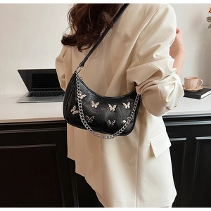 Détail du sac croissant noir avec papillons argentés sur cuir texturé et chaîne métal