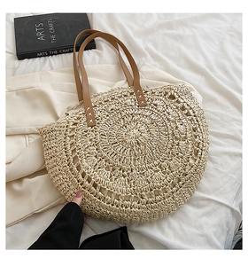 Detailed macro view of the reinforced cross-stitched handles on a beige woven straw tote bag