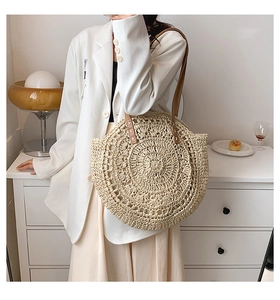 Detailed close-up of the woven straw texture and leather strap stitching on the tote bag