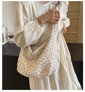 Detail of floral crossbody bag worn with a white dress in a casual cafe setting
