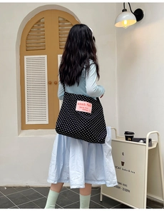 Detailed view of black polka dot canvas tote bag with pink logo patch on the front