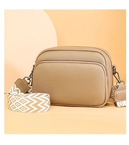 Gros plan du sac caméra en cuir kaki avec fermetures éclair et bandoulière en jacquard