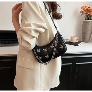 Détail d'un sac porté épaule noir en forme de lune avec charms papillons et chaîne argent