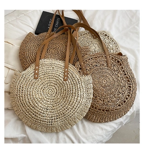 Detail of round straw shoulder bags with leather handles and spiral woven texture