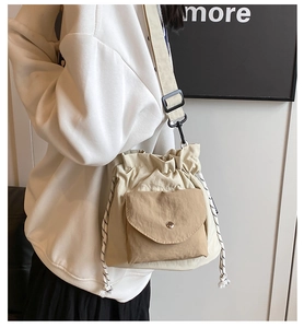 Close-up of beige nylon bucket bag with khaki front pocket and woven drawstring detail