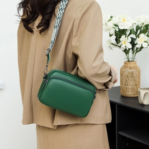 Dark green lychee leather crossbody bag with geometric woven strap on a model