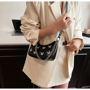 Detail of black crescent hobo bag with silver metal butterflies and chunky chain