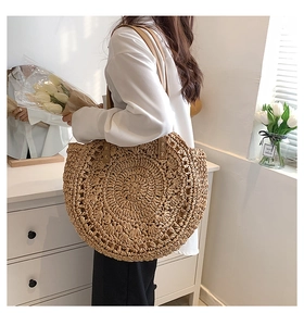 Close-up of semi-circle straw bag with leather straps and detailed ripple weave texture