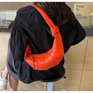 Detail of orange croissant shoulder bag with pleated PU leather and knotted strap design
