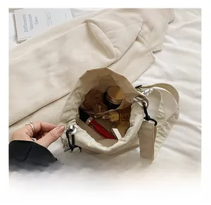 Top view showing internal capacity of the beige nylon drawstring bucket bag with makeup